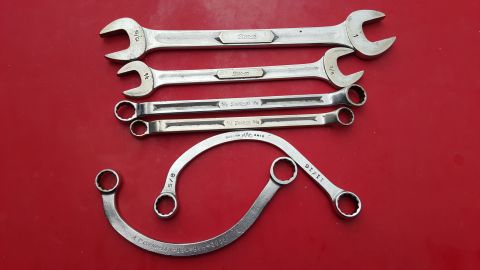 1965 Ford Mustang - A collection of various wrenches, some marked with brand names and sizes, laid out on a red surface.