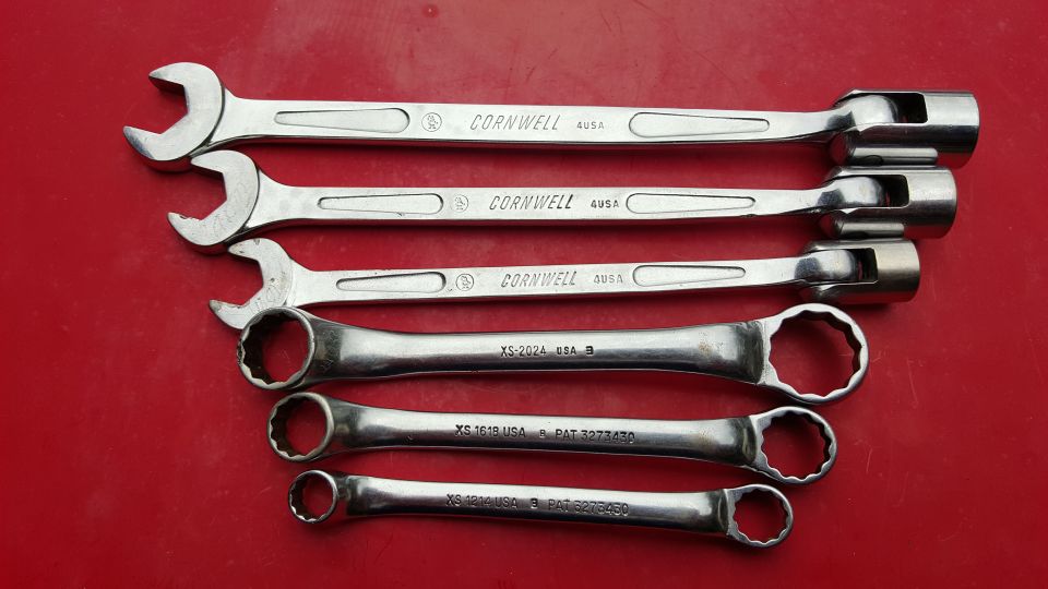 Five wrenches laid out on a red surface. Top three are Cornwell brand, bottom two have XS markings
