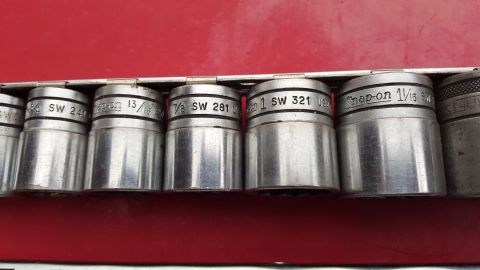 1965 Ford Mustang - A collection of metal sockets, some marked with 'Snap-on' and specific measurements, are neatly arranged in a holder.