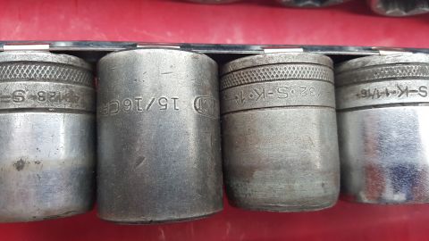 1965 Ford Mustang - A set of metal sockets with size markings is displayed on a red surface.