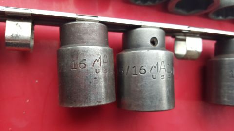 1965 Ford Mustang - Two MAC Tools sockets, marked '15' and '5/16', are mounted on a metal strip against a red surface.