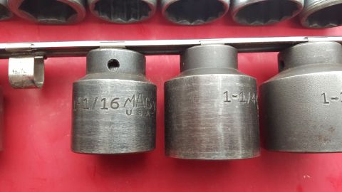 1965 Ford Mustang - A collection of sockets, some with size markings, are displayed on a rack.