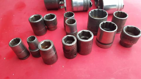 1965 Ford Mustang - A collection of various sized metal sockets are laid out on a red surface, suggesting a tool collection.