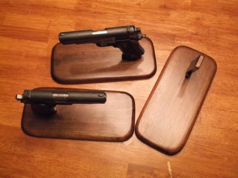 1995 Mercury Grand Marquis - Two handguns are displayed on wooden bases on a wooden surface, with a third empty base to the right.