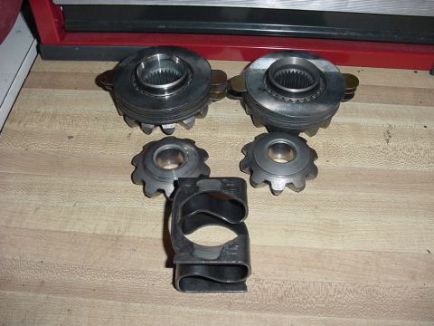 1989 Ford Bronco - Differential gears and a U-joint strap are laid out on a workbench.