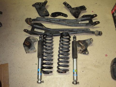 1996 Ford Bronco - Various suspension parts, including shocks and springs, are displayed on a concrete surface.