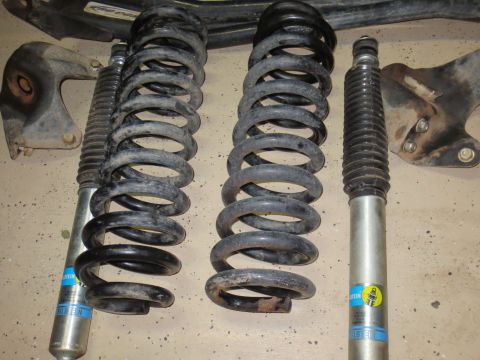 1996 Ford Bronco - Suspension components, including coil springs and shock absorbers, are laid out on a concrete surface.
