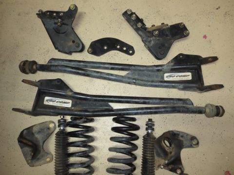 1996 Ford Bronco - A collection of Pro Comp suspension components, including control arms and shock absorbers, laid out on a concrete surface.