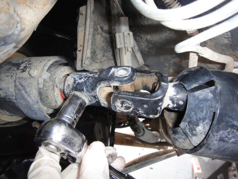 1988 Ford Bronco - A mechanic uses a socket wrench on a vehicle's steering universal joint.