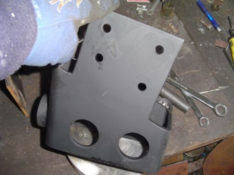 1993 Ford Bronco - A person in a blue glove holds a freshly painted metal bracket over a workbench with tools.