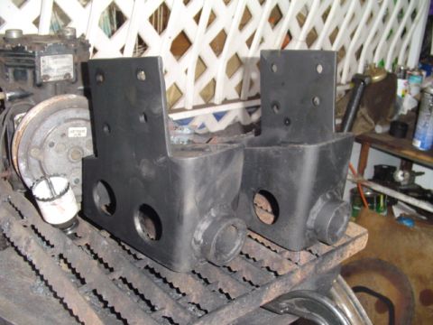 1993 Ford Bronco - Close view of a pair of freshly painted black fabricated steel spring/shackle brackets with multiple bolt holes and tubular bushing sleeves…