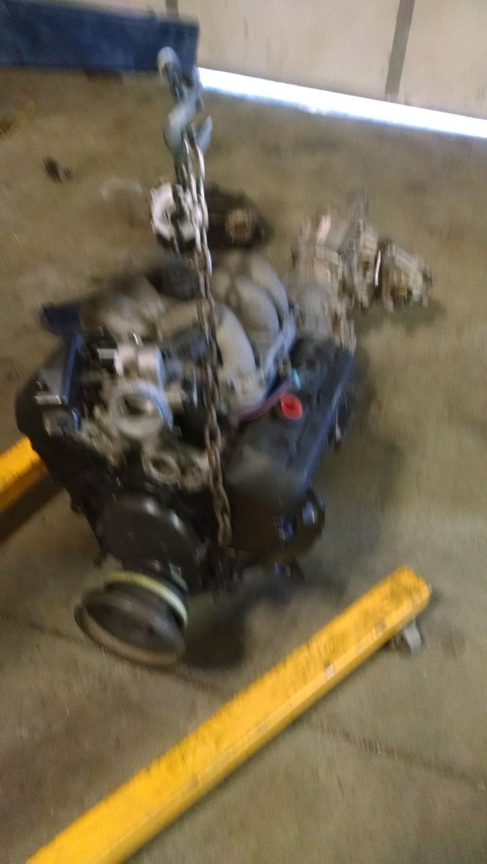 Engine suspended by a chain, with yellow support beams below
