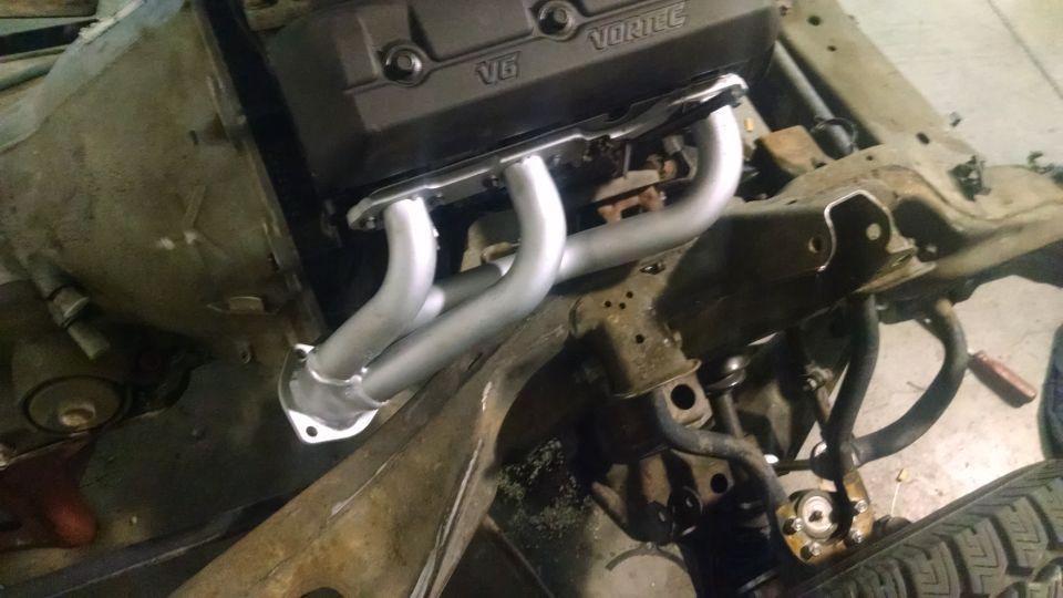 V6 Vortec engine block with exhaust manifold attached to frame