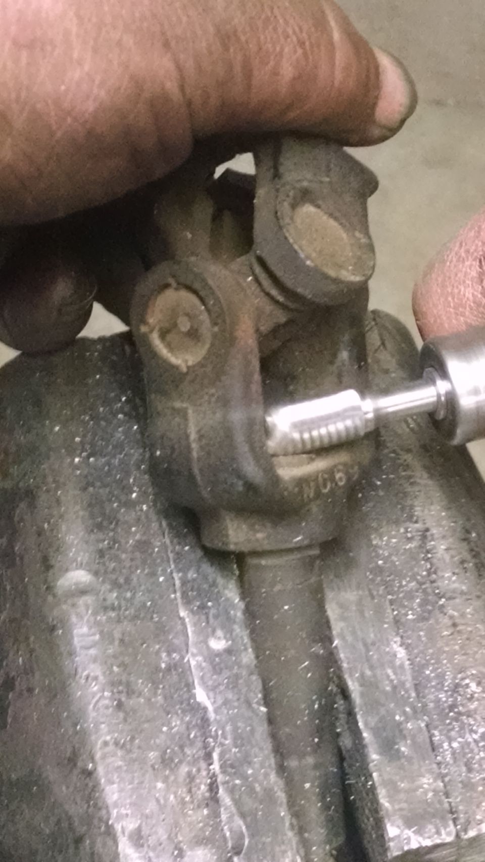 Close-up of a universal joint with a tool working on it. Part number 'WC6' is visible