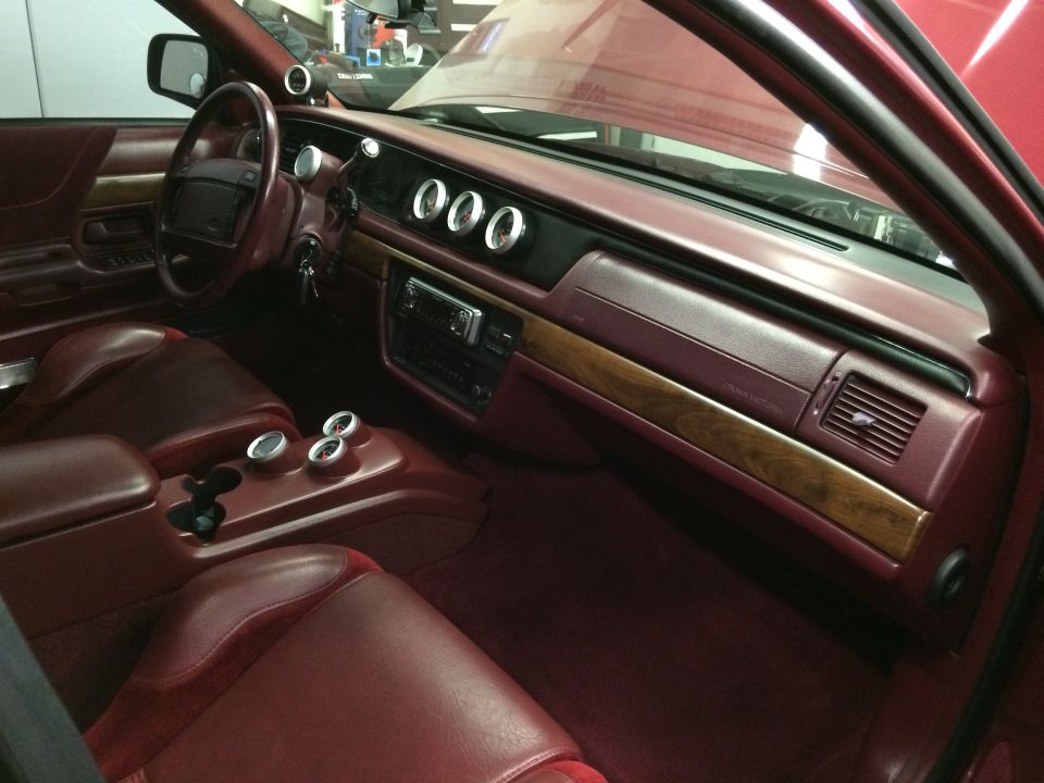 Maroon interior of a 1992 Ford Crown Victoria with custom gauges and wood trim