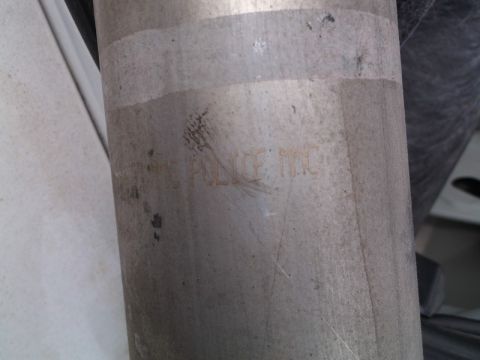 1999 Mercury Grand Marquis - Close-up of a metal exhaust pipe with "POLICE INC" stamped on it.