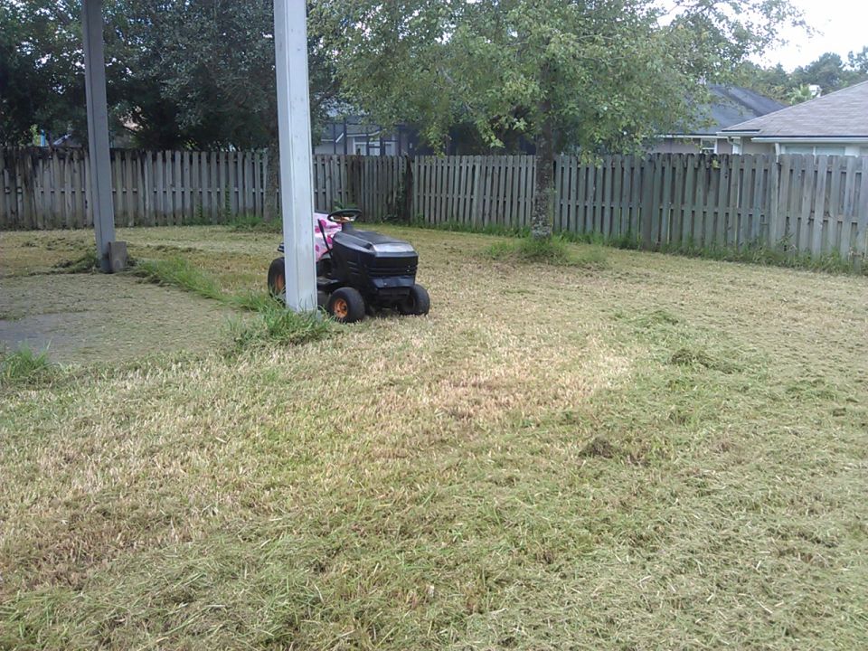 Riding lawn mower parked in a yard with cut grass