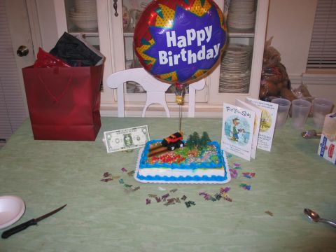1995 Ford Bronco - A birthday cake decorated with a toy truck and trees sits on a table with a happy birthday balloon and cards.