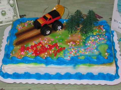 1995 Ford Bronco - A toy monster truck sits atop a birthday cake with 'Happy Birthday You' written in red icing.