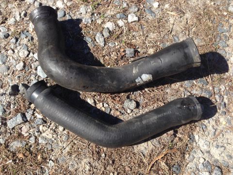 1979 Ford Bronco - Two black rubber radiator hoses are shown on a gravel surface, with text visible on one hose.