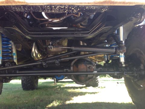 1979 Ford Bronco - Undercarriage view shows the suspension and drivetrain components of a 4x4 vehicle, including blue coilover shocks and a differential.