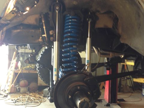 1979 Ford Bronco - Close-up of a vehicle's front suspension system, bright blue coil springs and silver shock absorbers.