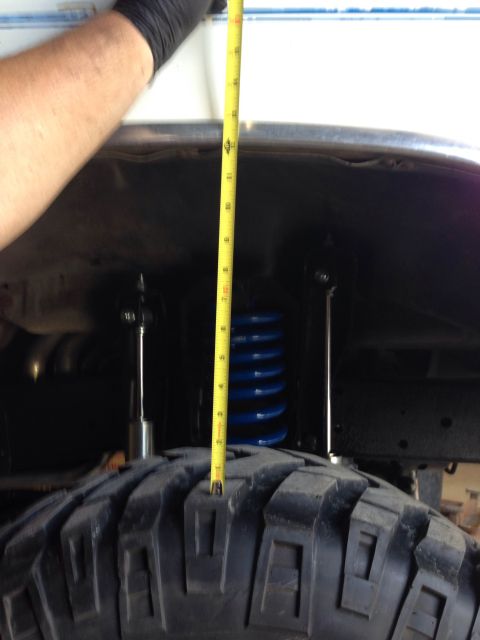1979 Ford Bronco - Measuring tire clearance with a tape measure, showing a blue coil spring.