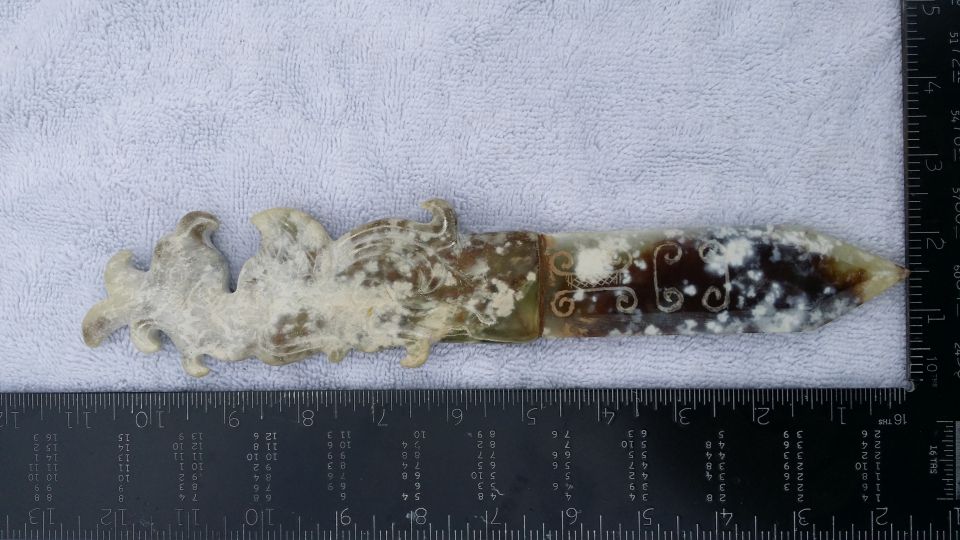 ornamental jade dagger with dragon motif, placed on a ruler