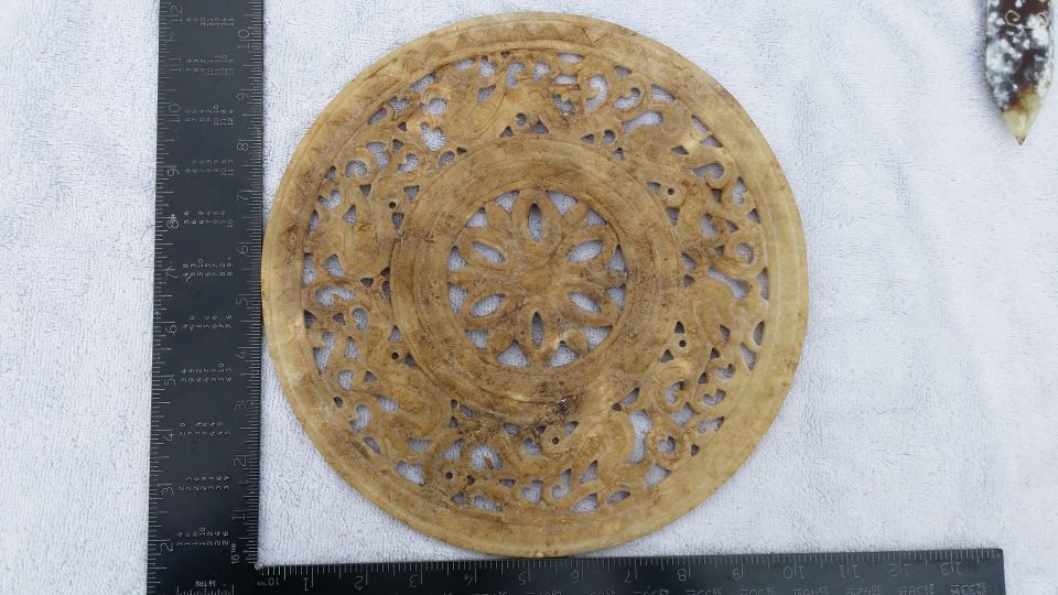 Ornate carved disc with ruler for scale
