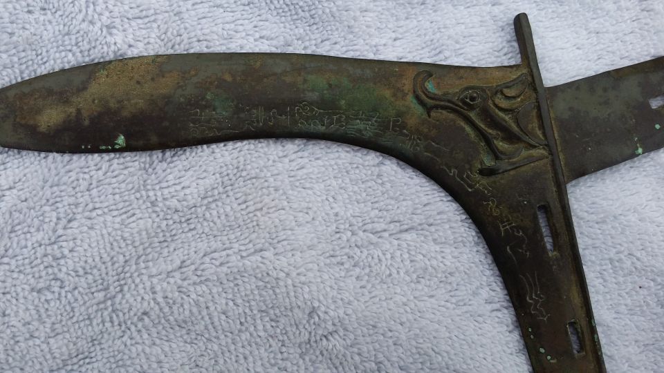 Close-up of an antique bronze sword hilt a dragon head and inscribed characters