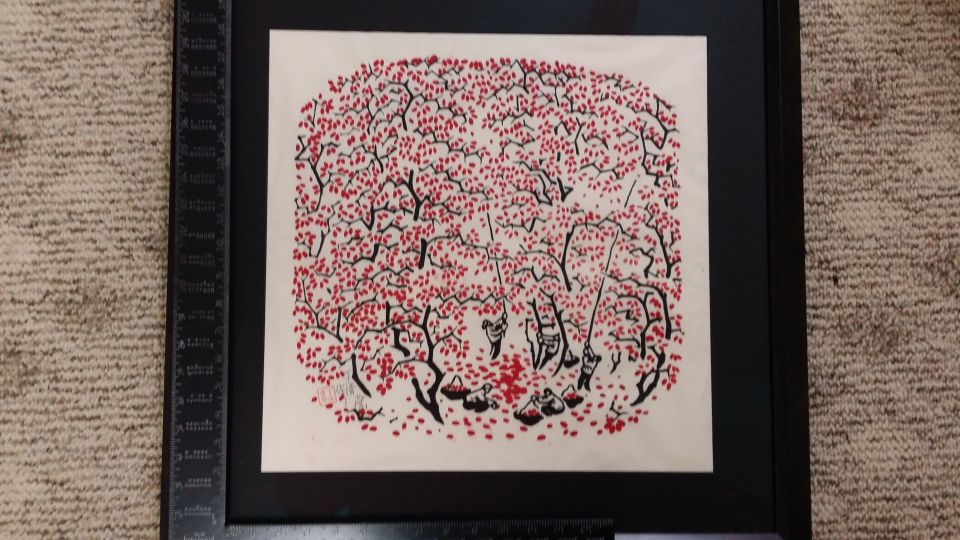 Framed artwork depicting figures harvesting fruit from trees with red leaves