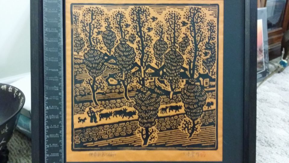 Framed woodblock print depicting a pastoral scene with trees, houses, and livestock