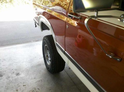 1982 Ford Bronco - Side profile of a brown and white 1982 Ford Bronco, highlighting its fender and wheel.