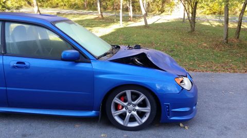 2007 Subaru Impreza - This blue Subaru Impreza has significant front-end damage, with the hood severely bent.