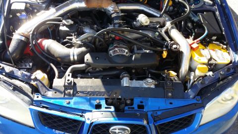 2007 Subaru Impreza - Engine bay of a blue Subaru, aftermarket intercooler piping and yellow top batteries.