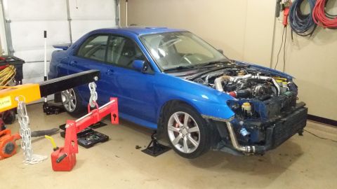 2007 Subaru Impreza - A blue Subaru Impreza is in a garage with its hood open and front bumper removed, undergoing maintenance.