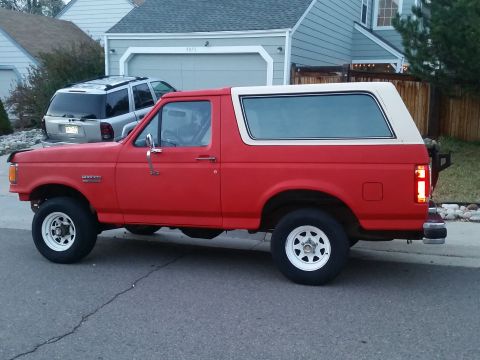 1988 Ford Bronco - This 1988 Ford Bronco is parked on a residential street with a house and driveway in the background.