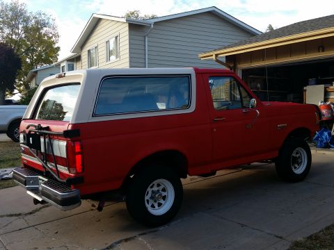 1988 Ford Bronco - This Ford Bronco is parked outside a residential garage, showing its side profile and two-tone paint scheme.
