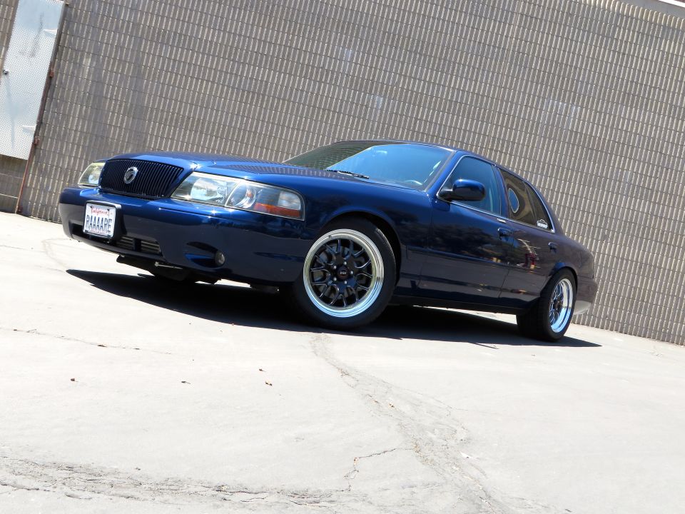 Lowered blue Mercury Grand Marquis sedan with black alloy wheels on pavement