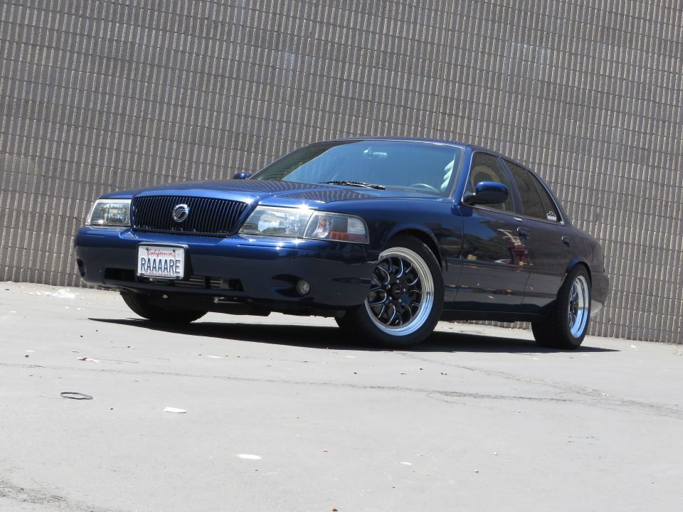 Dark blue 2003 Mercury Marauder with aftermarket wheels parked in front of a textured wall
