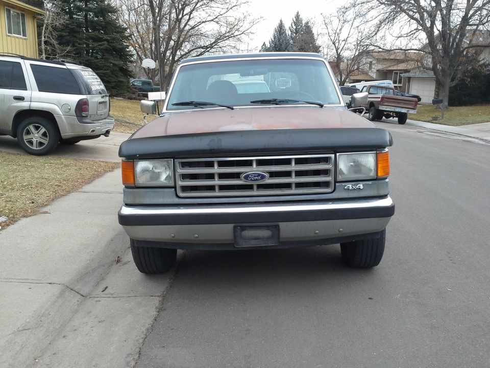Brown and gray Ford Bronco with a hood deflector, parked on a residential street