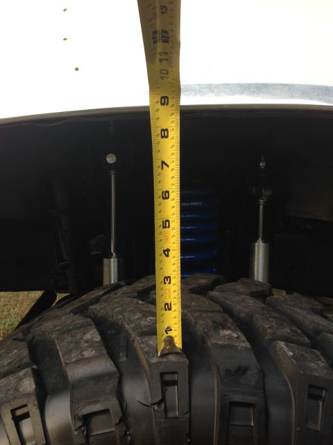 1979 Ford Bronco - A tape measure is used to measure the suspension lift on a vehicle. The image focuses on the tire and suspension components.