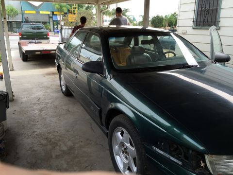 1993 Ford Taurus - A 1993 Ford Taurus is parked under a carport, with a trailer and pickup truck visible in the background.