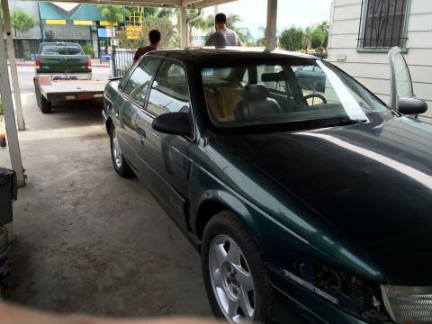 1993 Ford Taurus - A dark green sedan is parked under a carport, with a pickup truck and trailer visible in the background.
