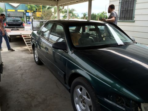 1993 Ford Taurus - A dark green sedan is parked under a carport while a man stands near the driver's side door.