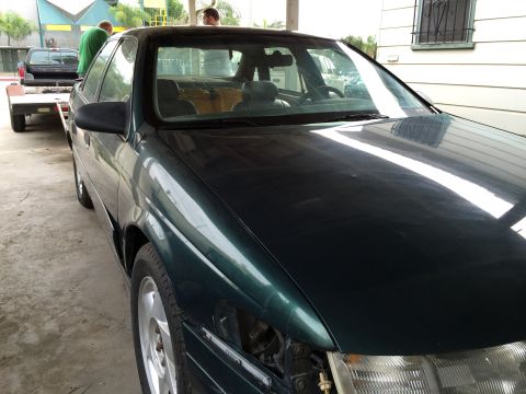 1993 Ford Taurus - Dark green sedan, possibly a 1995 model, is being towed on a trailer.