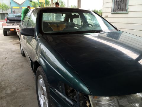 1993 Ford Taurus - A dark green 1993 Ford Taurus is seen from a 3/4 front angle while being towed on a trailer.