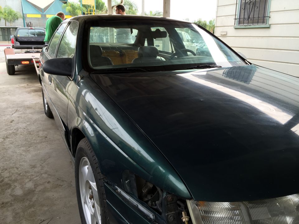 1993 Ford Taurus, dark green, 3/4 front view, being towed