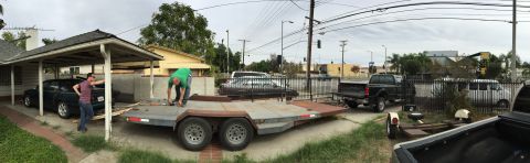 1993 Ford Taurus - Two men are by a car trailer and a dark sedan under a carport, with a truck in the background.