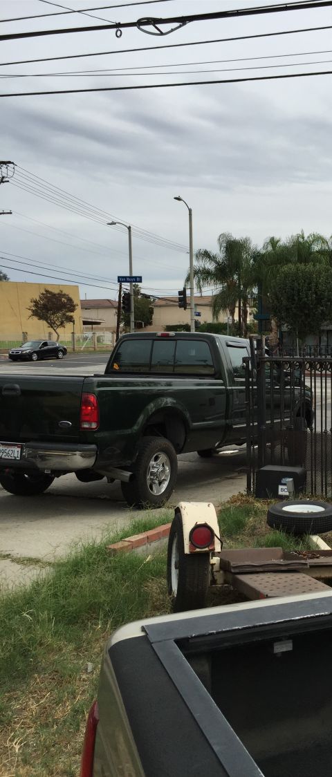 1993 Ford Taurus - A dark green Ford F-250 Super Duty pickup truck is parked on the side of the road.